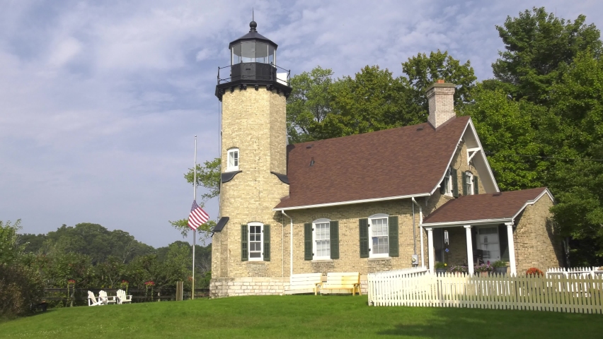 White River lighthouse at White Lake Michigan. This structure features a residence as well as the lighthouse, all built from brick. Static close up shot featuring grass and garden in the foreground.