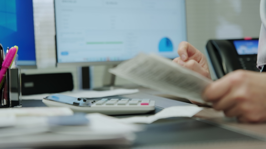 Close up shot of Woman accounting sit at desk using computer, make data analysis, check receipt, workday in office.  Royalty-Free Stock Footage #1097710997