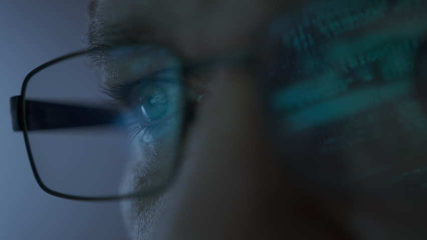 Close up shot of portrait of software engineer working on computer. Line of hack code run in reflection on eyeglasses  | Shutterstock HD Video #1097711027
