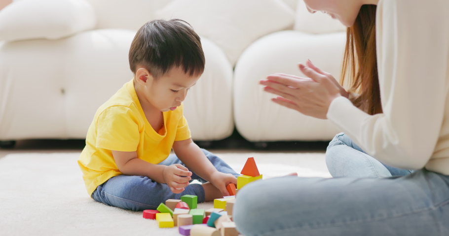Asian happy mother and her child son are playing with building blocks together in living room at home | Shutterstock HD Video #1097711781