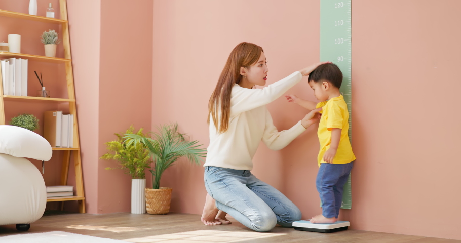 asian mother is leading her child son to measure height and she is worried about his development Royalty-Free Stock Footage #1097711787