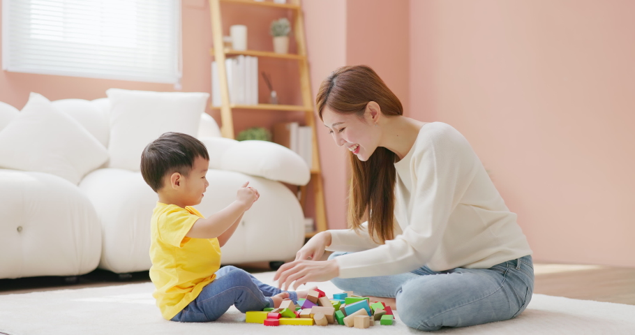 Asian happy mother and her child son are playing with building blocks together in living room at home | Shutterstock HD Video #1097711799
