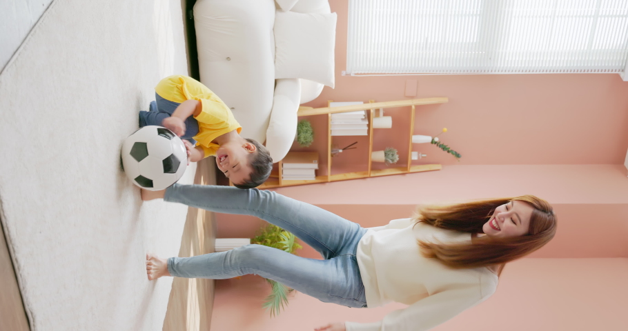 Vertical of asian happy mother and her child son are playing with soccer ball together in living room at home | Shutterstock HD Video #1097711809