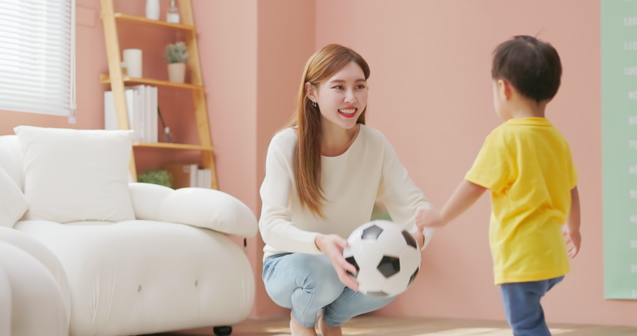 Slow motion of asian happy mother and her child son are playing with soccer ball together in living room at home | Shutterstock HD Video #1097711819