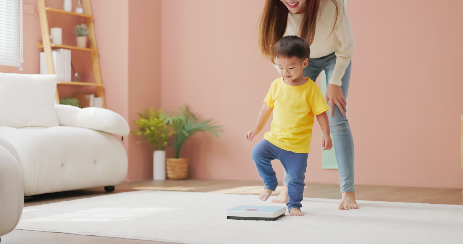 Slow motion of asian happy mother is leading her child son to stand on a weight scale and she encourage him by clap hands about good body development | Shutterstock HD Video #1097711821