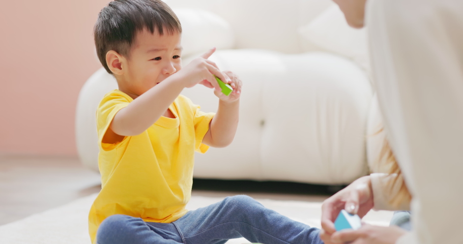 Asian happy mother and her child son are playing with building blocks together in living room at home | Shutterstock HD Video #1097711823