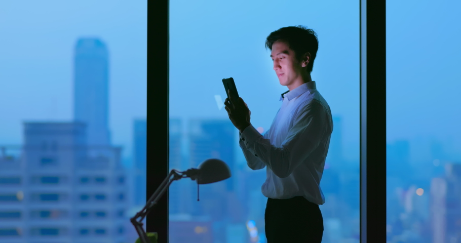 Side view of Asian business man standing in office using smartphone at night | Shutterstock HD Video #1097711829