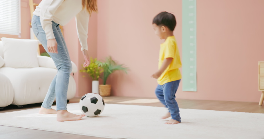 Asian happy mother and her child son are playing with soccer ball together in living room at home | Shutterstock HD Video #1097711831