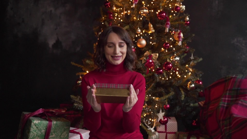 Happy smiling young woman waiting for good Christmas present, lady with disappointment opening box with surprise on background of xmas tree at living room. Female looking at camera incomprehensibly. | Shutterstock HD Video #1097712261