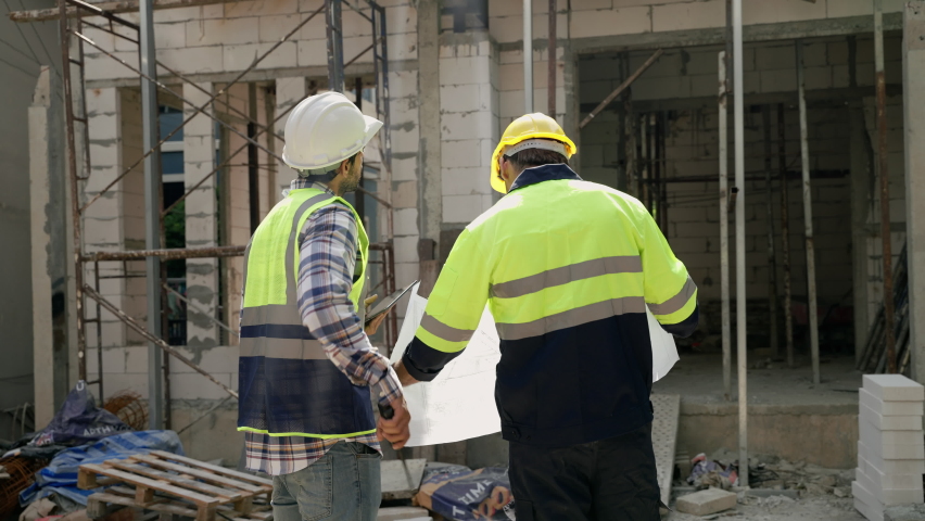 Construction engineer and foreman walking holding blueprints walking inspect at construction site to meet specs, construction concept, engineer, business | Shutterstock HD Video #1097712335