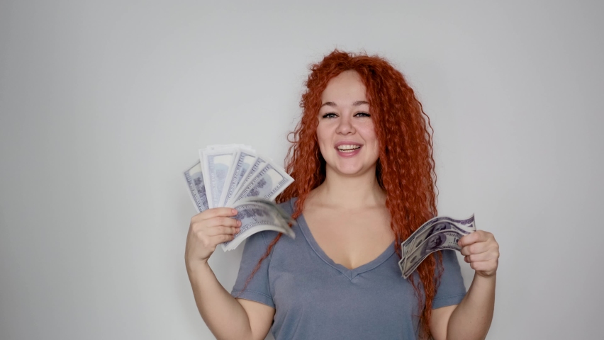 A rich red-haired woman holds a wad of dollars in her hand. Concept of financial success | Shutterstock HD Video #1097713215