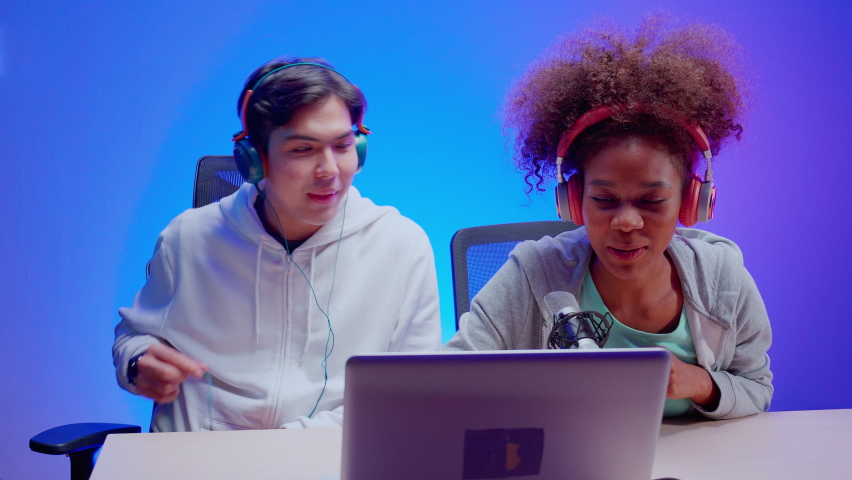 Young African American woman and asian man a podcast interview and conversation together in studio, male and female host wearing headset talking with microphone, radio and broadcast concept. | Shutterstock HD Video #1097713257