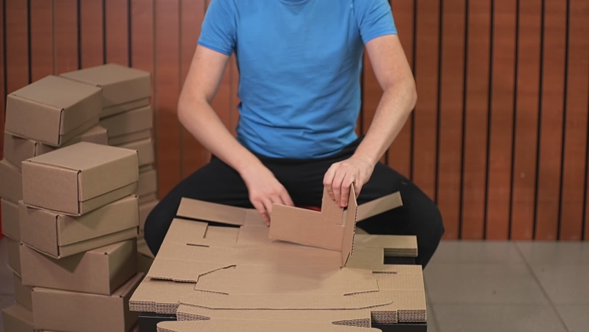 A man folds a cardboard box according to the instructions, sitting on a chair. High-quality Full HD video recording. slow motion video | Shutterstock HD Video #1097713701