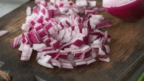 Chopped red onion on wooden cutting board. Cooking vegetable salad. 4k video