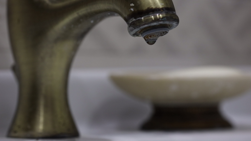 Water Drops Drip From The Vintage Bronze Faucet. Hands Close The Vintage Bronze Faucet In The Bathroom. 60 FPS, 4k, ProRes