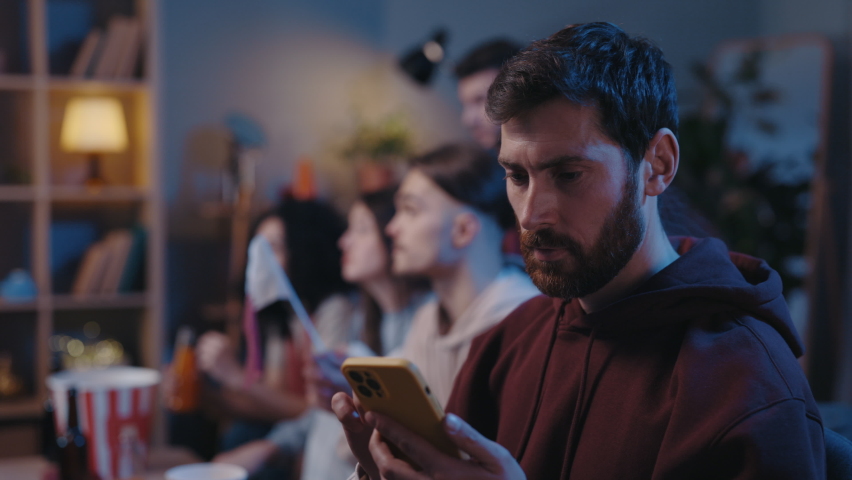 Concentrated bearded man looking attentively at his device screen and rejoicing while looking at results of sports betting during football game. Male fans cheering at home concept Royalty-Free Stock Footage #1097720679