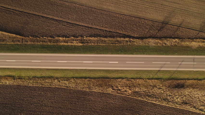 Aerial shot of coach bus driving along the road through countryside landscape in autumn, top view