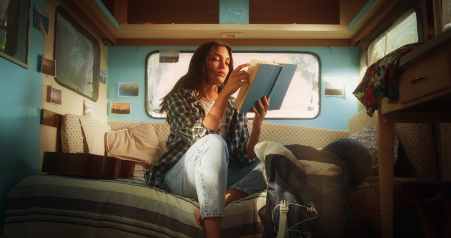 Young Adult Female Enjoying Her Time in a Motorhome, Relaxing and Reading an Adventure Book Story. Beautiful Girl Camping in a Caravan, Having a Journey to Rediscover Her True Self. Royalty-Free Stock Footage #1097724063