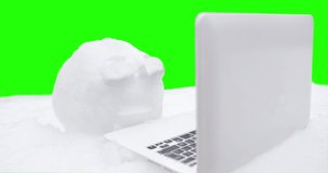 Snowball with eyes using laptop, notebook. Funny, interesting concept of snow winter character with face and living eyes watching, blinking. Winter, Christmas online concept. Green screen
