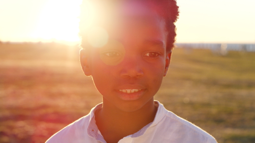 Child, face and park with lens flare, sunset and outdoor with travel and holiday headshot, peace and calm with nature. Sun mockup, portrait and freedom with African American boy kid in Atlanta.