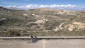 Young woman rides a road bike on the rural road with a scenic view, aerial drone video