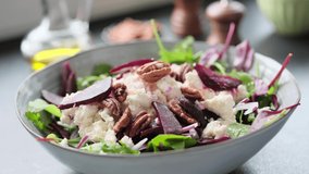 Salad making video 4k. Fresh nutrition salad of beetroot, babyspinat, onions, arugula, pecan and white soft cheese. Homemade cooking footage.