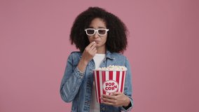 Portrait of a woman watching a drama movie in the cinema. Young girl holding a bucket of popcorn and wearing 3d glasses. High quality 4k footage