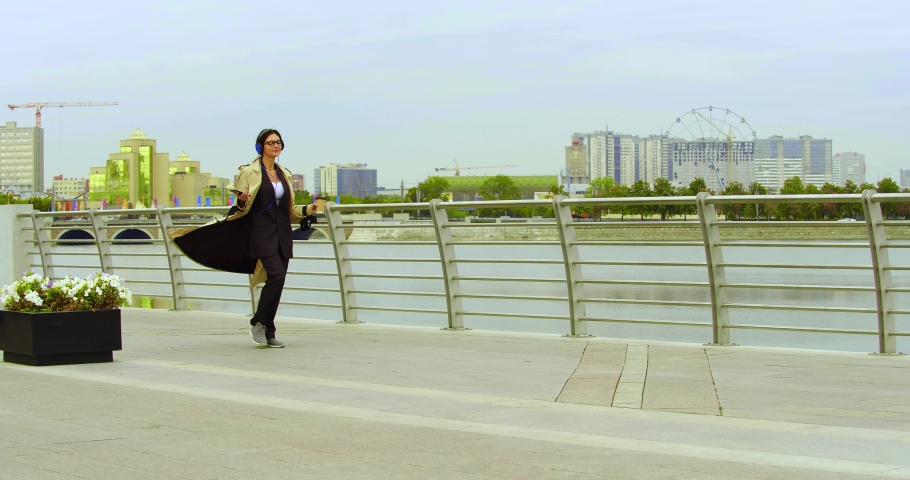 Dancing business woman - she is listening to music on headphones using an online smartphone application. Slow motion 4k footage.