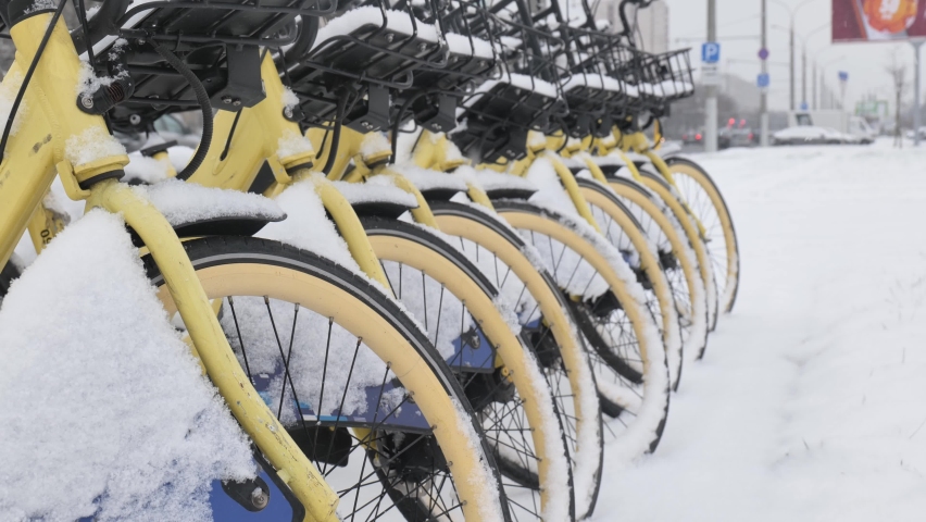 Bicycles covered with snow stand during a snowfall