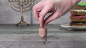 Hand twists a dreidel with the letters Shin, Hey, Nun and Gimel (Hebrew). In the background are hanukkah and donuts. Hanukkah. Jewish holidays (152) - Powered by Shutterstock - Get 15% off with code: PIKWIZARD15