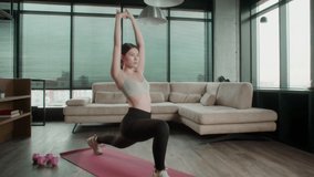 Young Sporty Asian Woman in sportswear doing stretching yoga exercises. Female fitness practicing leg stretching exercises on yoga mat at home. Pretty lady burning calories, practice pilates