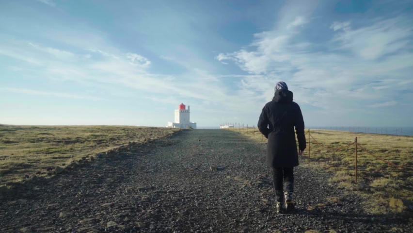 person tourist walking towards  Dyrhólaey Lighthouse 