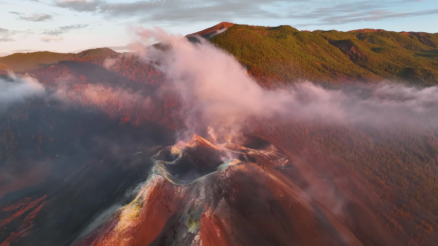 Aerial view of Volcano at Cumbre Vieja, La Palma at sunset with white and black smoke plumes and ashes in the Canary Islands