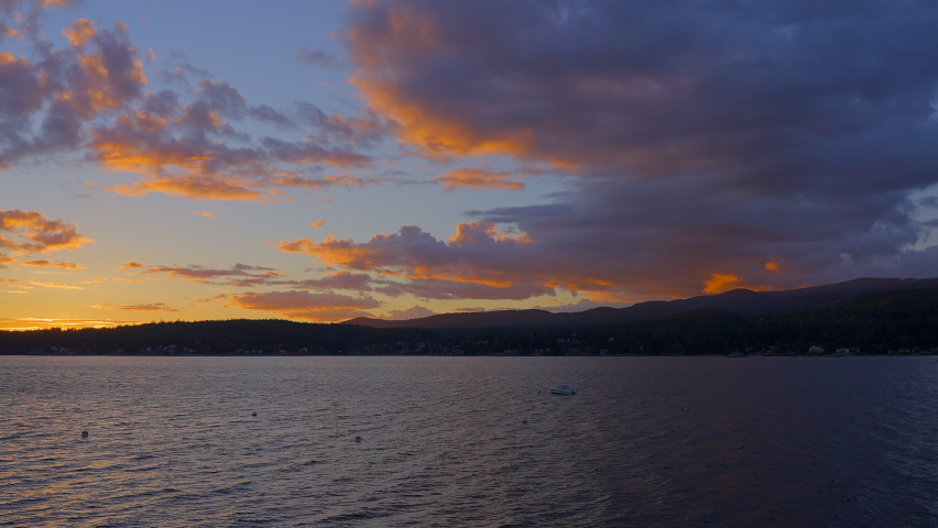Establishing shot of ocean sunset over mountains in slow motion at summer day in Vancouver, Canada, North America. Evening time on September 2022. Still camera. ProRes 422 HQ.