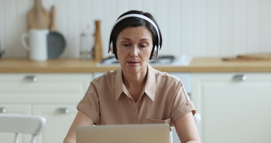 Older woman get medical consultation, talks to therapist share health complaints use laptop and video call application sit at table in kitchen at home. Professional e-services, virtual meeting event Royalty-Free Stock Footage #1097785079