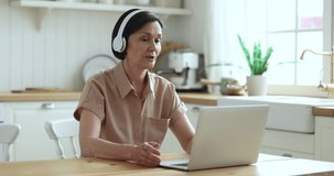 Mature tutor wear wireless headphones leads on-line class to learners using laptop and videoconference application, working from home, get or provide professional electronic services. Virtual meeting