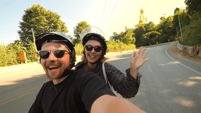 Young Mixed Raced Tourist Couple Riding Motorbike in Asia and Taking Funny Selfie Videos Using Action Camera High Quality 4K Slowmotion Footage. Thailand. - Powered by Shutterstock - Get 15% off with code: PIKWIZARD15