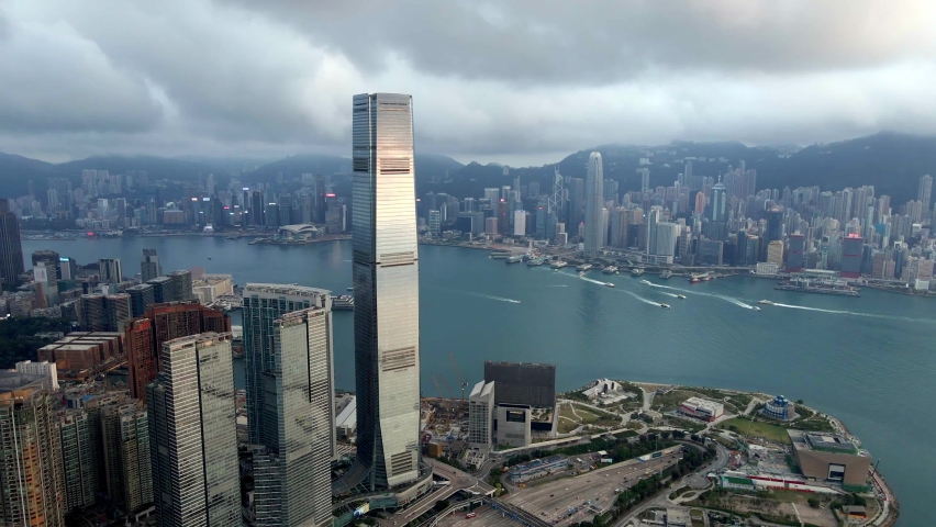 Skyscrapers in Hong Kong. Sunset reflections on the windows of ICC building. Boats. Cloudy day. Hong Kong Island. Financial hub. Aerial drone view.Popular iconic travel destination in Asia. China