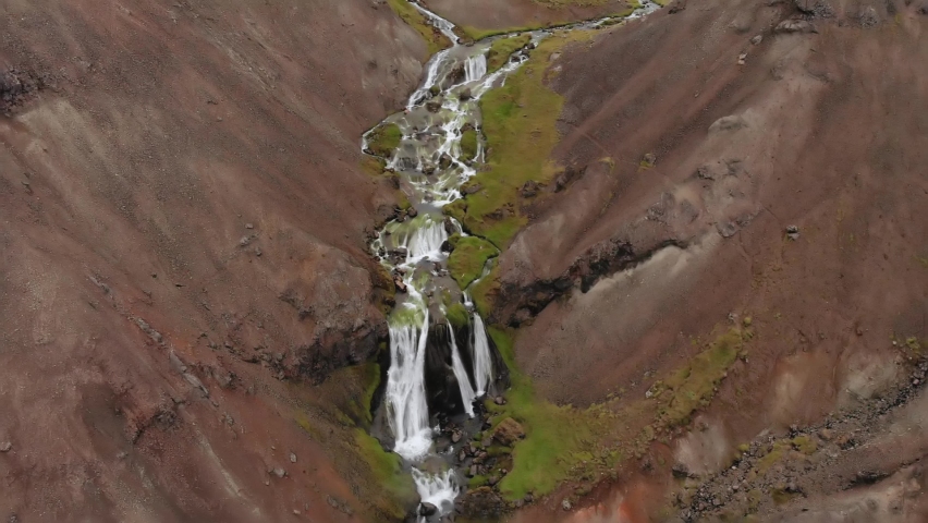 Aerial small stream waterfall in Iceland in the brown and green mountains