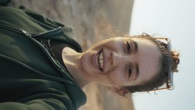 Vertical video - Female traveler or content creator on video call while outside. Woman having conversation on video using mobile cellphone while traveling in outdoors in desert. Waving and talking