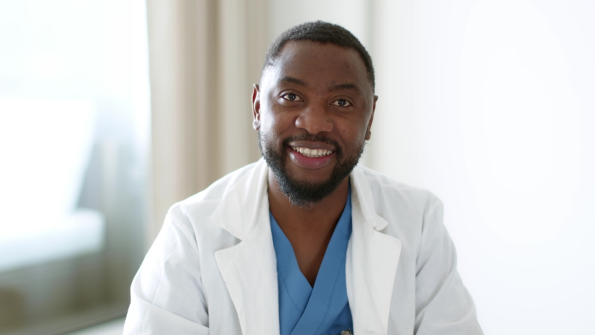 Telemedicine concept. Close up portrait of positive professional african american man doctor waving hand to camera and start talking, consulting patient online, slow motion Royalty-Free Stock Footage #1097794681