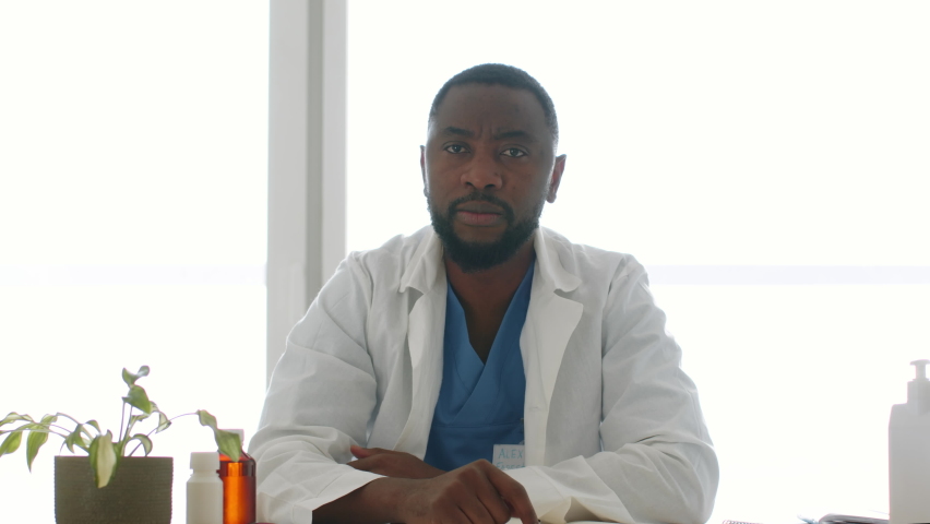 Online medical consultation. Camera pov portrait of young professional african american man doctor talking to subscribers, recording blog video at office, slow motion, free space Royalty-Free Stock Footage #1097794683