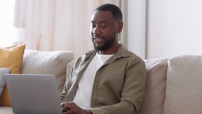 Benefits of remote work. Young black man freelancer typing on laptop at home, his loving girlfriend coming and embracing him, looking together at laptop, tracking shot, slow motion, free space - Powered by Shutterstock - Get 15% off with code: PIKWIZARD15