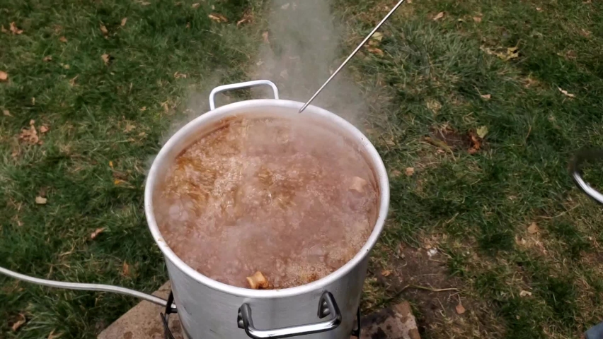 Checking temp and tenderness of large whole Turkey while being deep fried in large pot.  Royalty-Free Stock Footage #1097800699