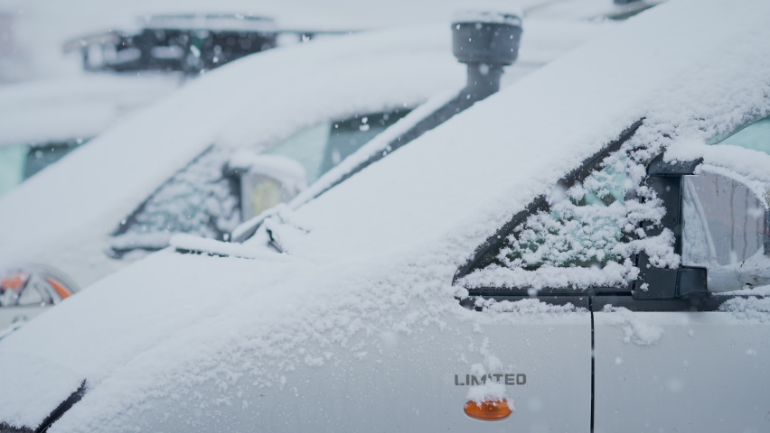 Close up - Snow flakes begin to fall on car roof, slow motion, cinematic.