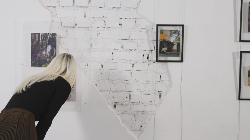 Beautiful blonde in the art gallery. A woman looks at the work of a contemporary artist.