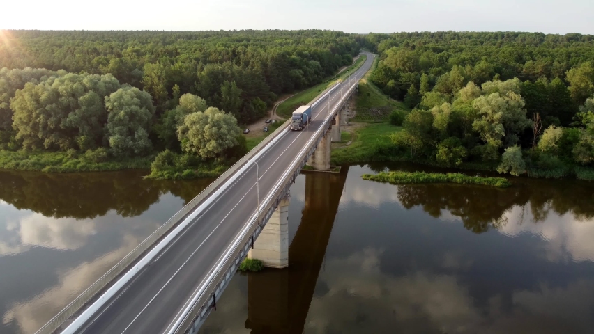Autonomous semi-truck with a trailer, controlled by artificial intelligence, drives over a bridge over the river. Cargo delivery, transportation of the future. Artificial intelligence. Self driving Royalty-Free Stock Footage #1097812757