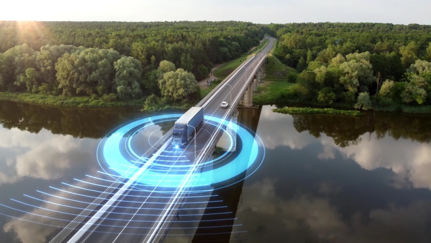 Autonomous semi-truck with a trailer, controlled by artificial intelligence, drives over a bridge over the river. Cargo delivery, transportation of the future. Artificial intelligence. Self driving