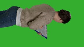 Vertical video: Profile close up of casual adult analyzing clipboard papers in studio, standing on greenscreen background. Positive woman taking notes on files writing information on documents