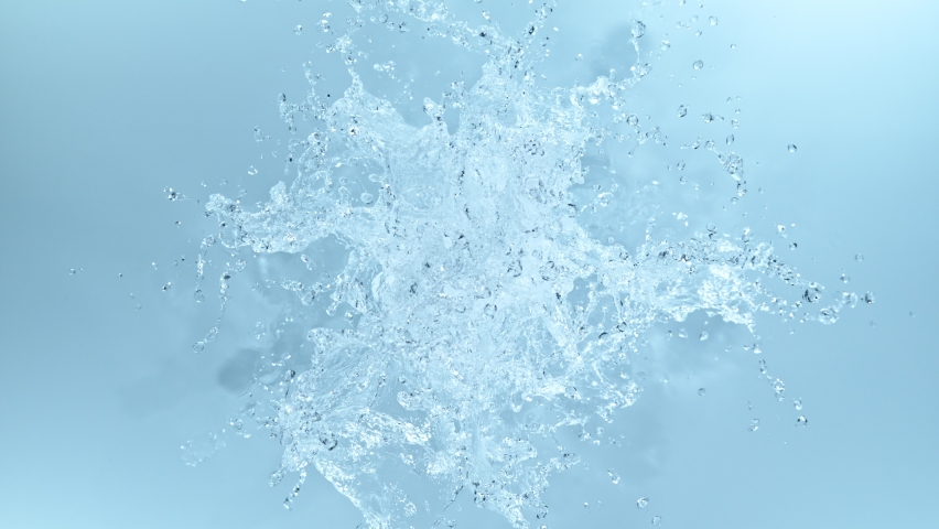 Super slow motion of splashing water on blue background. Filmed on high speed cinema camera, 1000 fps. High angle view, studio shot.